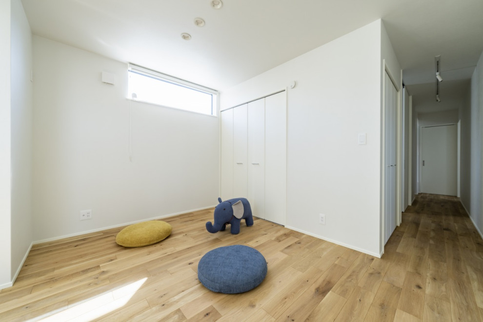 Bild på ett mellanstort funkis könsneutralt småbarnsrum kombinerat med lekrum, med vita väggar, ljust trägolv och brunt golv