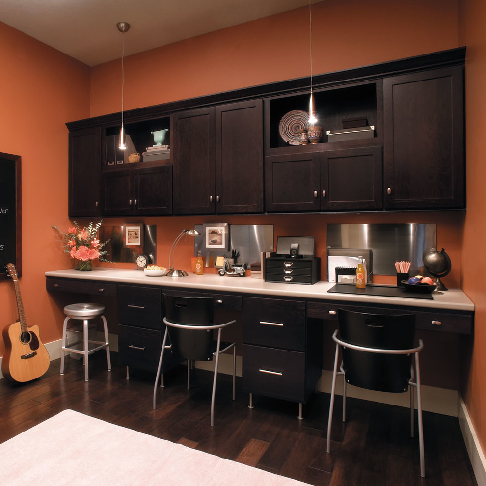 Design ideas for a mid-sized transitional study room in Other with orange walls, dark hardwood floors, a built-in desk and brown floor.