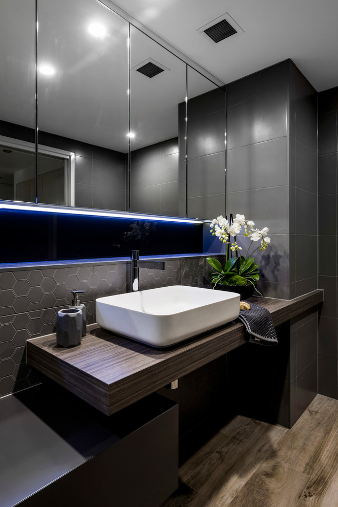 Design ideas for a mid-sized modern bathroom in Brisbane with furniture-like cabinets, distressed cabinets, a curbless shower, a wall-mount toilet, brown tile, porcelain tile, brown walls, ceramic floors, a vessel sink and laminate benchtops.
