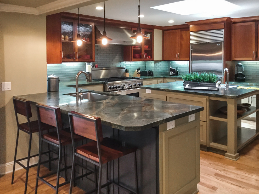 Example of a mid-sized transitional u-shaped medium tone wood floor kitchen design with an undermount sink, granite countertops, glass tile backsplash, stainless steel appliances, an island, shaker cabinets, medium tone wood cabinets and blue backsplash