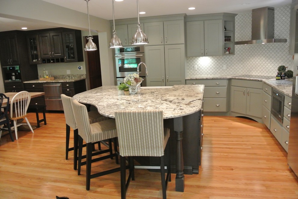 Inspiration for a large transitional l-shaped light wood floor eat-in kitchen remodel in Boston with a farmhouse sink, shaker cabinets, gray cabinets, granite countertops, white backsplash, ceramic backsplash, stainless steel appliances, an island and gray countertops