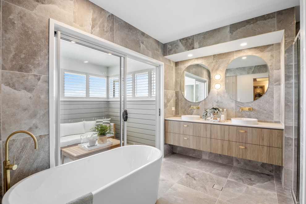 Inredning av ett modernt vit vitt badrum, med släta luckor, beige skåp, ett fristående badkar, grå kakel, grå väggar, ett fristående handfat och grått golv