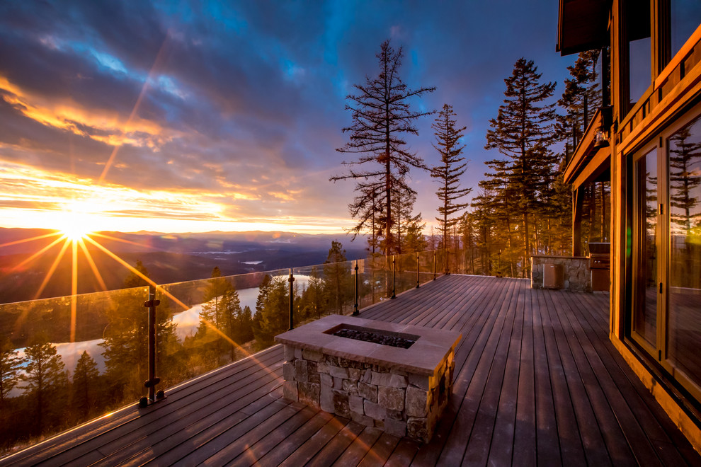 Example of a large mountain style backyard deck design with a fire pit and no cover