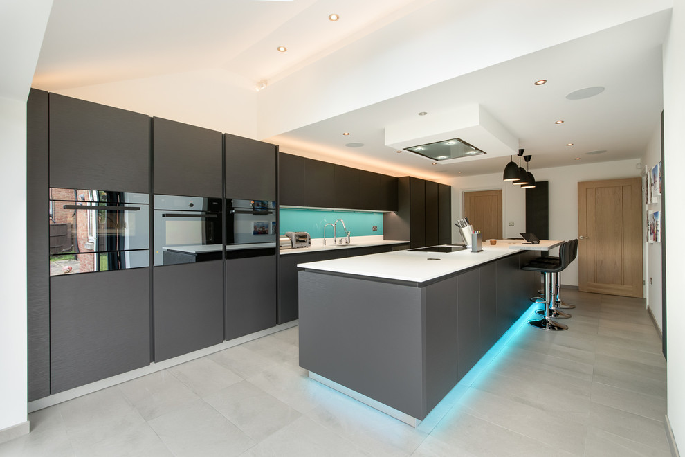 Inspiration for a large contemporary single-wall eat-in kitchen in Buckinghamshire with an undermount sink, flat-panel cabinets, black cabinets, quartz benchtops, blue splashback, glass sheet splashback, panelled appliances, ceramic floors, with island, grey floor and white benchtop.