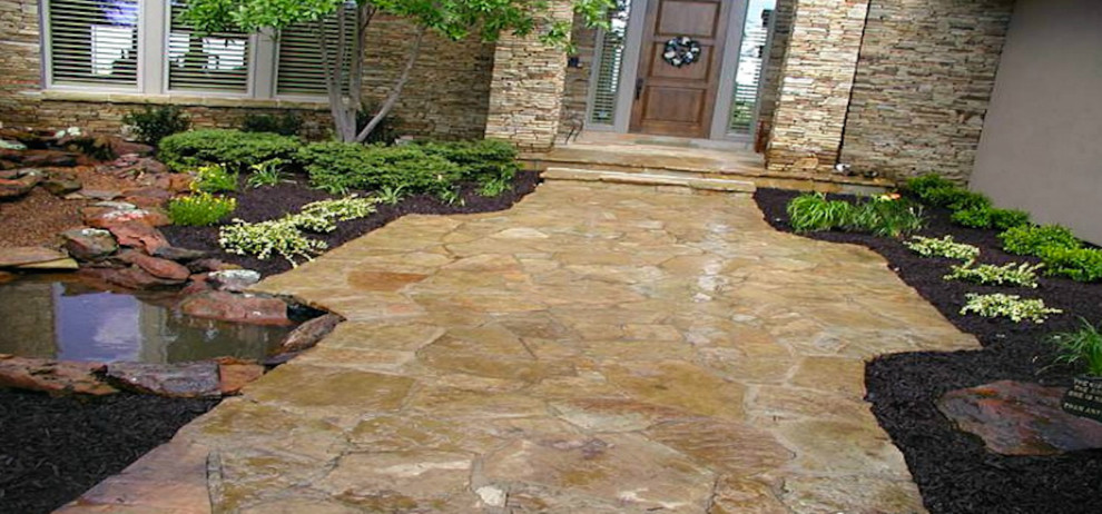 Photo of a mid-sized mediterranean courtyard patio in Kansas City with a water feature, natural stone pavers and no cover.