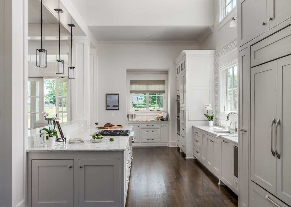 Transitional l-shaped dark wood floor and brown floor open concept kitchen photo in Nashville with an undermount sink, beaded inset cabinets, white cabinets, quartz countertops, white backsplash, stone tile backsplash, stainless steel appliances, an island and white countertops