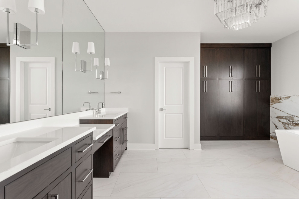 Design ideas for a medium sized modern ensuite bathroom in Indianapolis with flat-panel cabinets, dark wood cabinets, a freestanding bath, a built-in shower, a two-piece toilet, beige tiles, porcelain tiles, white walls, ceramic flooring, a submerged sink, white floors, a hinged door, white worktops, a shower bench, double sinks and a built in vanity unit.