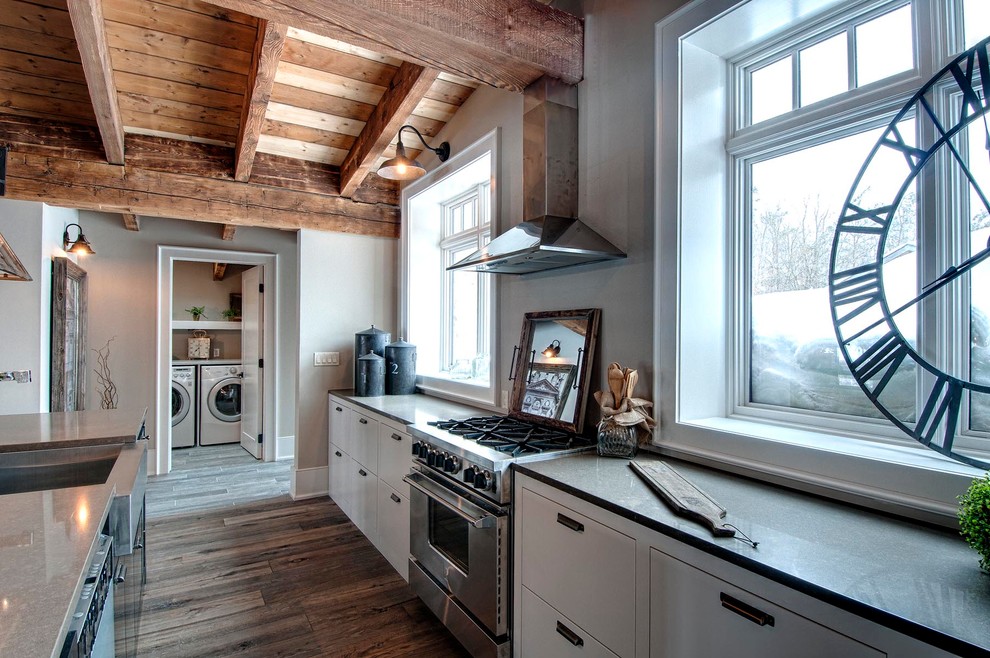 Inspiration for a country l-shaped kitchen pantry in Toronto with a farmhouse sink, flat-panel cabinets, white cabinets, quartz benchtops, stainless steel appliances, medium hardwood floors and with island.