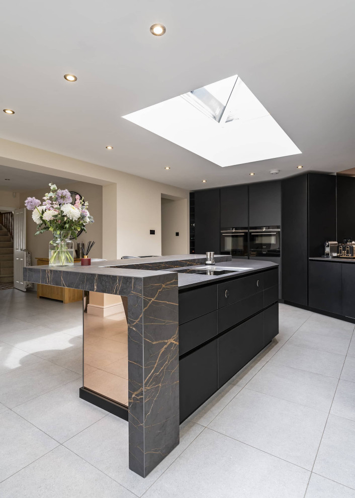 This is an example of a medium sized modern kitchen/diner in Oxfordshire with an integrated sink, glass-front cabinets, black cabinets, quartz worktops, glass sheet splashback, black appliances, ceramic flooring, an island, grey floors, multicoloured worktops, a coffered ceiling and feature lighting.