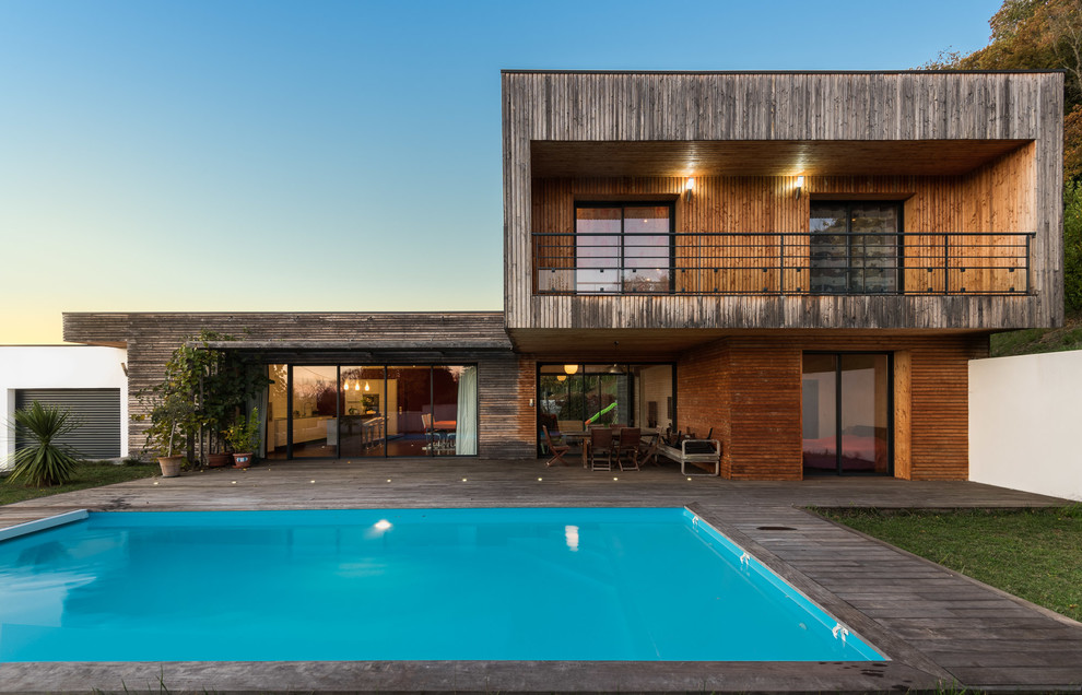 Photo of a beach style house exterior in Bordeaux with wood siding and a flat roof.