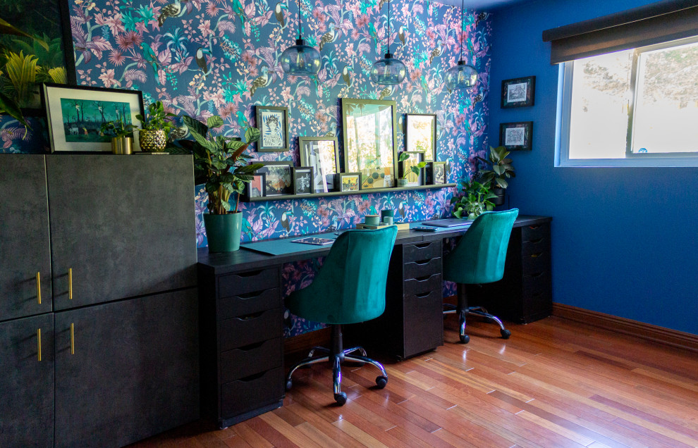 Mittelgroßes Nähzimmer mit blauer Wandfarbe, braunem Holzboden und freistehendem Schreibtisch in San Diego