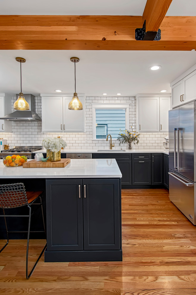 Inspiration for a mid-sized arts and crafts l-shaped eat-in kitchen in Seattle with an undermount sink, flat-panel cabinets, blue cabinets, quartz benchtops, white splashback, ceramic splashback, stainless steel appliances, medium hardwood floors, with island, brown floor and white benchtop.