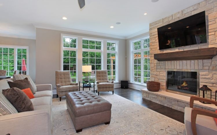 Photo of an expansive traditional open concept living room in Chicago with beige walls, dark hardwood floors, a standard fireplace, a stone fireplace surround and a wall-mounted tv.