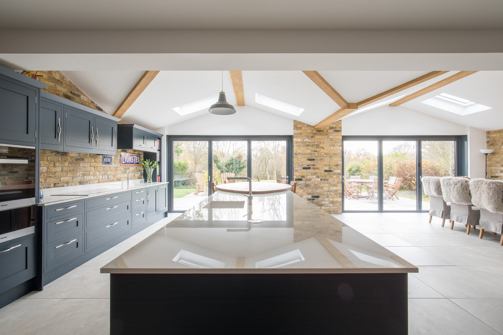 Inspiration for a large contemporary eat-in kitchen in Sussex with quartz benchtops, black appliances and with island.