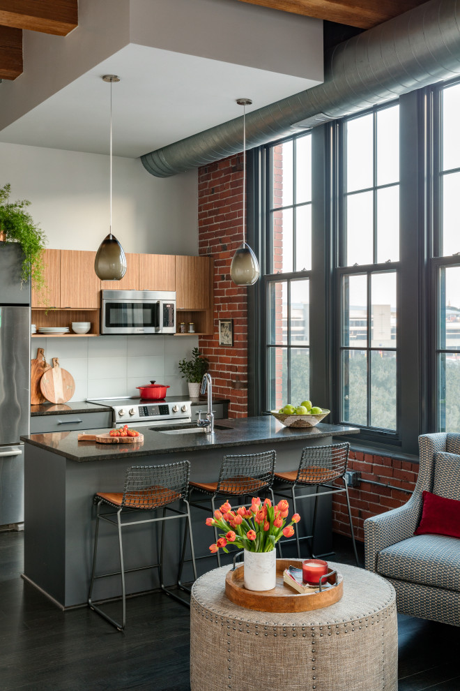 Inspiration for a mid-sized industrial galley separate kitchen in Boston with an undermount sink, flat-panel cabinets, stainless steel appliances, dark hardwood floors and with island.