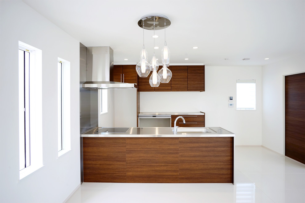 This is an example of a large modern single-wall open plan kitchen in Other with an integrated sink, beaded inset cabinets, dark wood cabinets, stainless steel benchtops, metallic splashback, glass sheet splashback, stainless steel appliances, a peninsula, white floor and wallpaper.