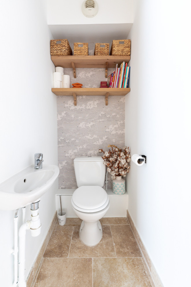 This is an example of a medium sized mediterranean cloakroom in Paris with a one-piece toilet, white walls, travertine flooring, a wall-mounted sink, quartz worktops, beige floors, white worktops and wallpapered walls.