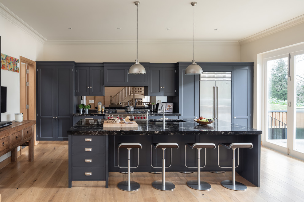 Design ideas for a transitional kitchen in Kent with an undermount sink, shaker cabinets, black cabinets, mirror splashback, stainless steel appliances, light hardwood floors, with island, beige floor and black benchtop.