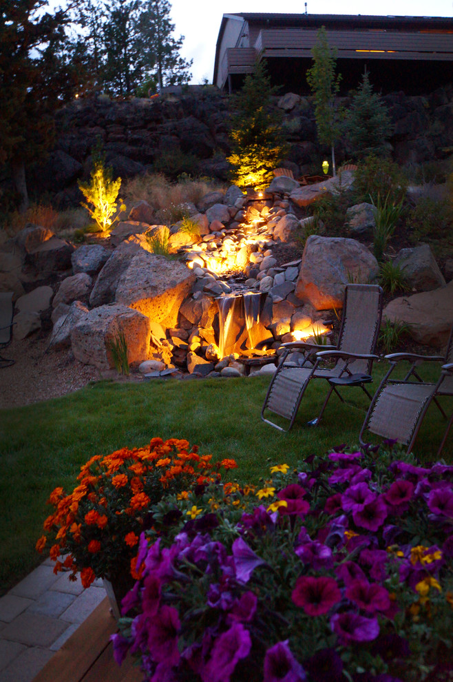 This is an example of a large arts and crafts sloped garden in Other with a fire feature and brick pavers.