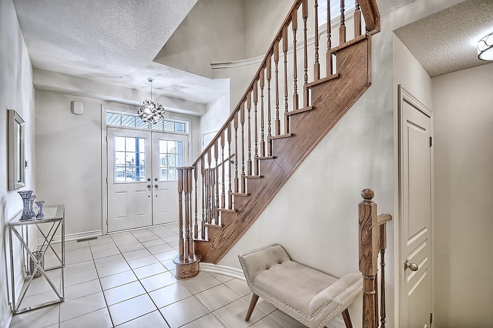Example of a mid-sized transitional ceramic tile and beige floor foyer design in Toronto with beige walls and a white front door