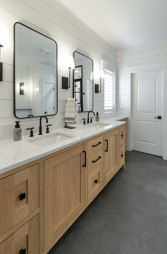This is an example of a large modern ensuite bathroom in Milwaukee with recessed-panel cabinets, light wood cabinets, a freestanding bath, a built-in shower, white tiles, ceramic tiles, white walls, ceramic flooring, a submerged sink, quartz worktops, grey floors, a hinged door, white worktops, an enclosed toilet, double sinks, a freestanding vanity unit and tongue and groove walls.