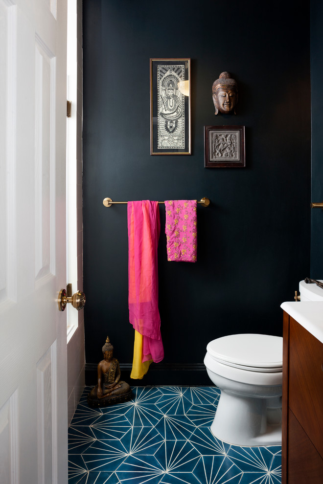 This is an example of a mid-sized eclectic powder room in DC Metro with a console sink, dark wood cabinets, a one-piece toilet, blue tile, black walls and concrete floors.