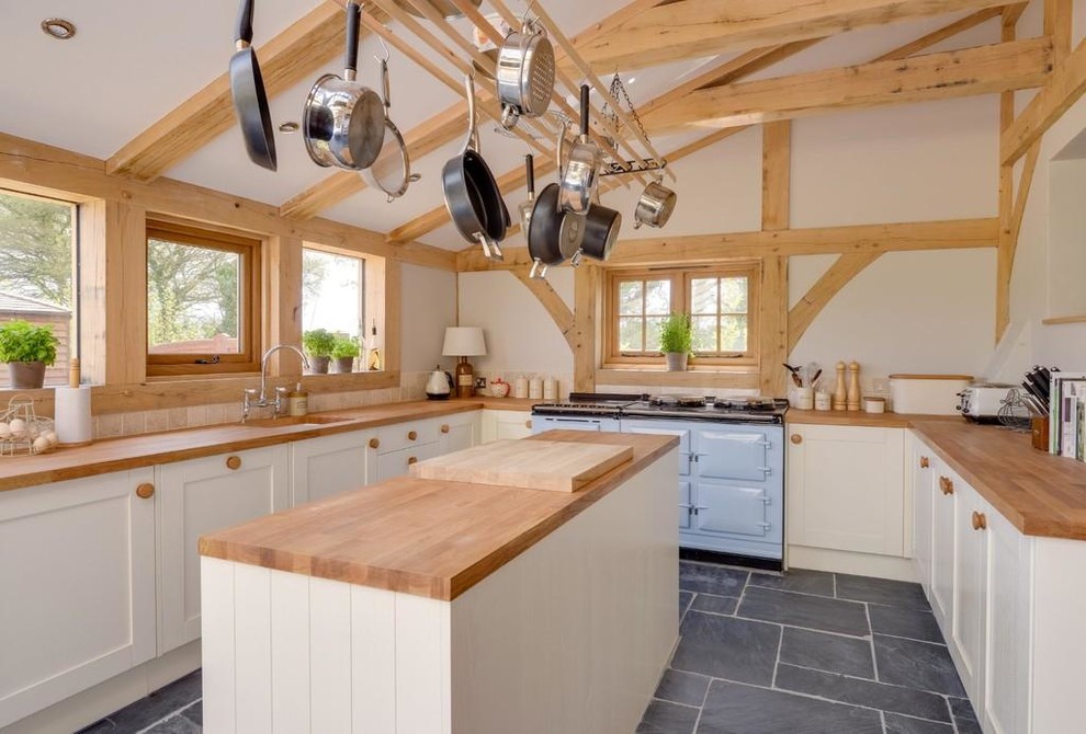 Photo of a country u-shaped kitchen in Sussex with a single-bowl sink, shaker cabinets, white cabinets, wood benchtops, beige splashback, coloured appliances and with island.