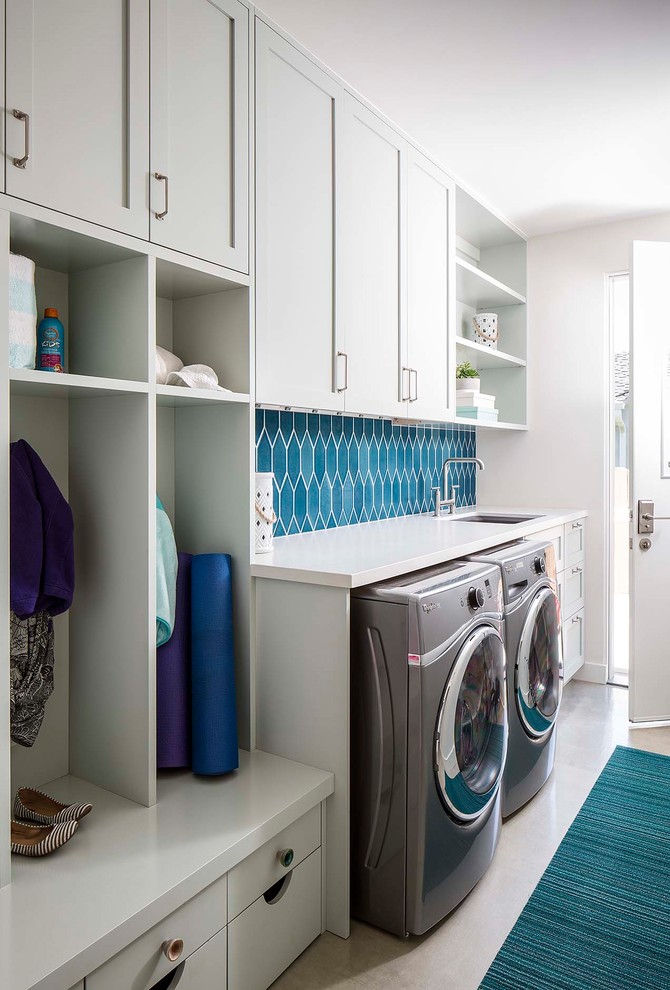 Photo of a transitional single-wall utility room in San Diego with shaker cabinets, grey cabinets, white walls, a side-by-side washer and dryer and white benchtop.