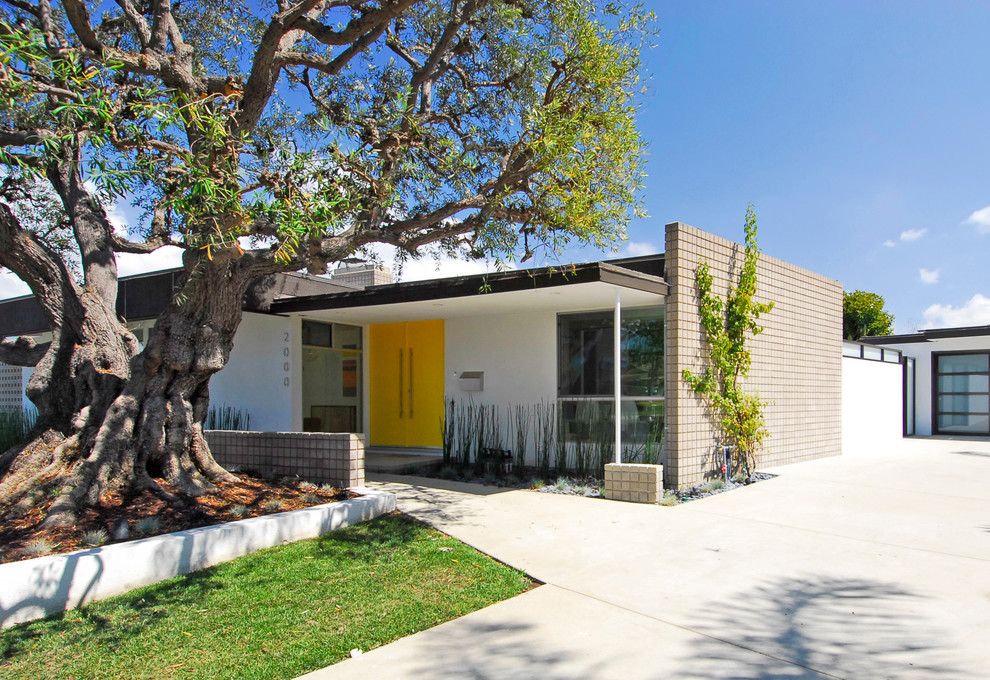 This is an example of a mid-sized midcentury one-storey stucco white exterior in Orange County with a flat roof.