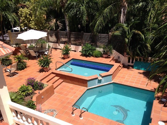 Mid-sized tropical courtyard custom-shaped natural pool in Baltimore with a water feature and tile.