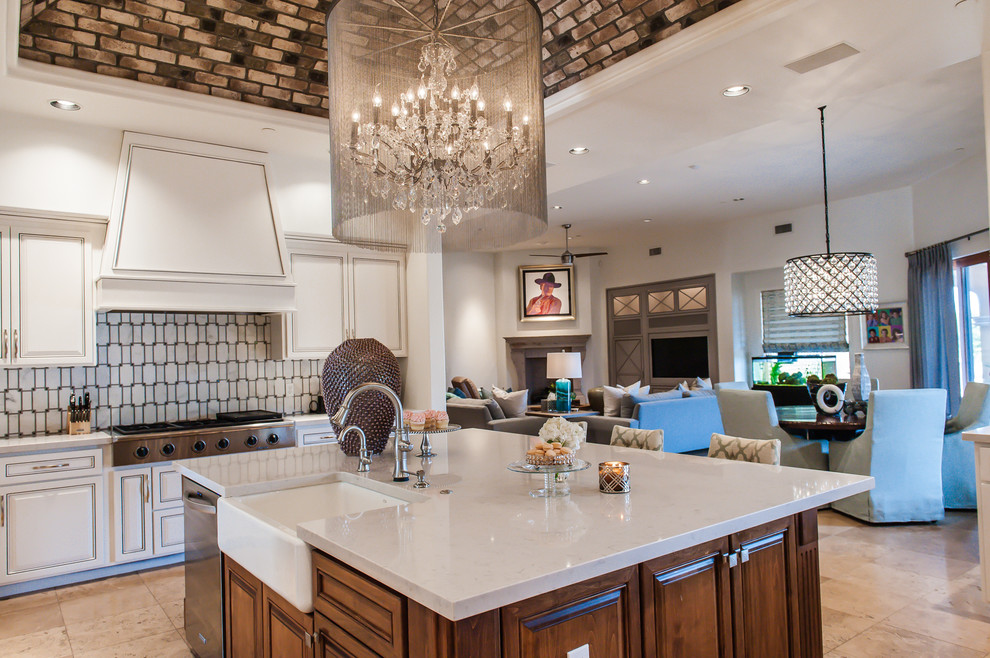Example of a large transitional single-wall travertine floor open concept kitchen design in Phoenix with a farmhouse sink, raised-panel cabinets, white cabinets, marble countertops, white backsplash, stone tile backsplash, stainless steel appliances and an island