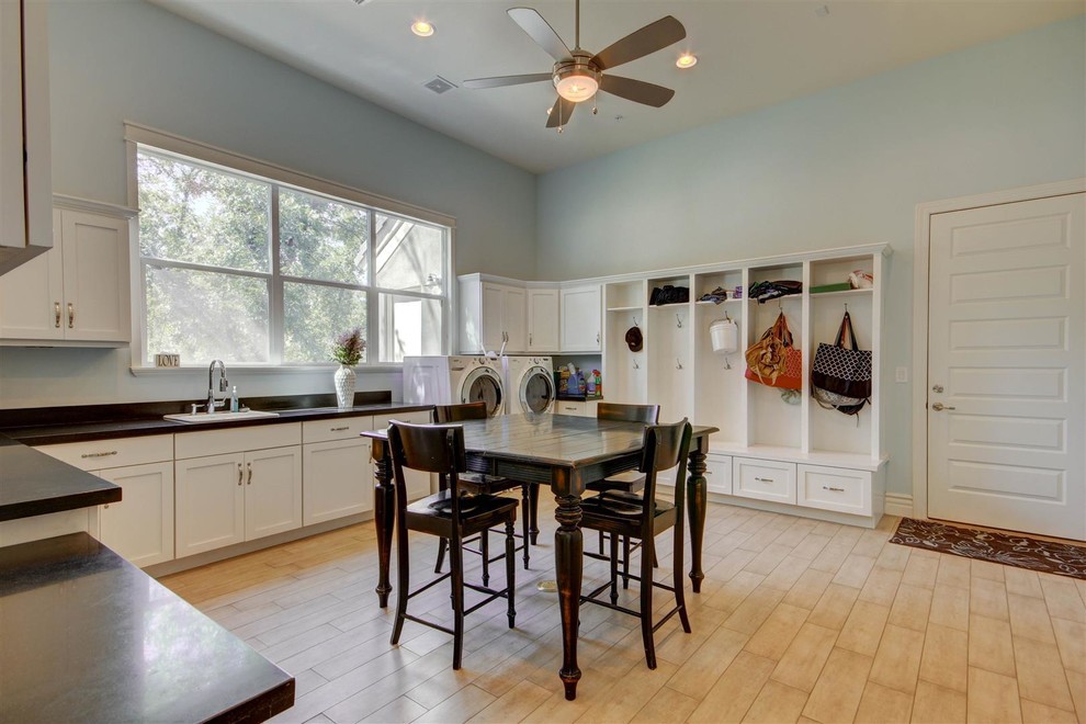 This is an example of an expansive transitional l-shaped utility room in Phoenix with a drop-in sink, shaker cabinets, white cabinets, solid surface benchtops, blue walls, light hardwood floors and a side-by-side washer and dryer.