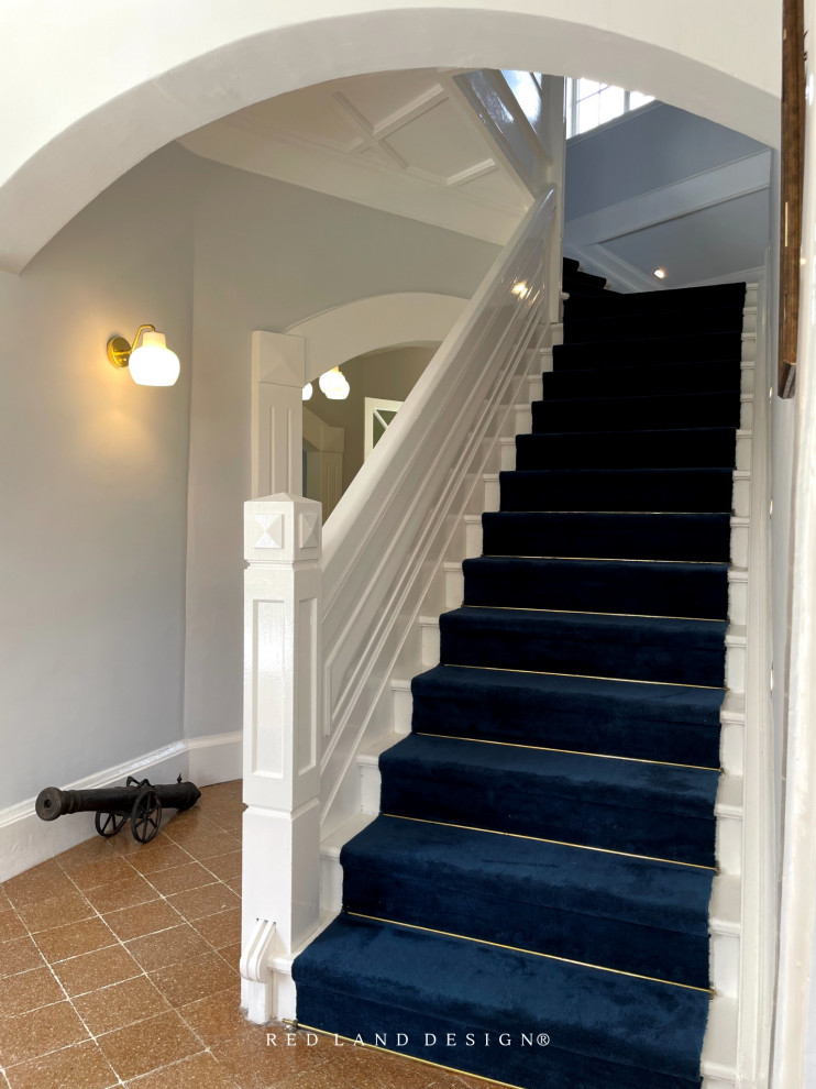 Photo of a small victorian painted wood l-shaped wood railing staircase in Other with carpeted risers and brick walls.