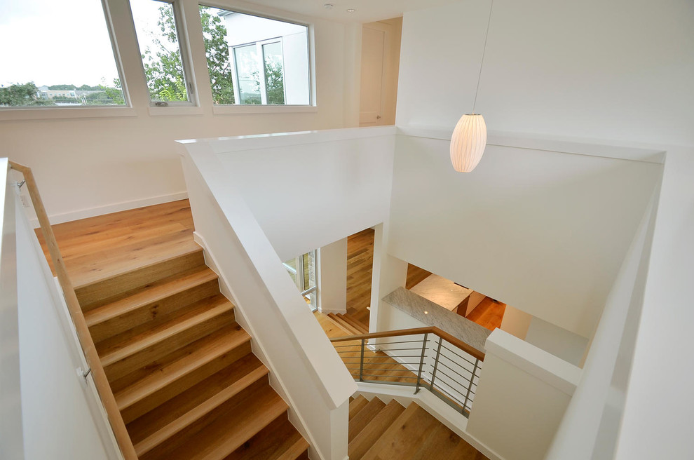 This is an example of a large modern wood u-shaped staircase in Austin with wood risers.