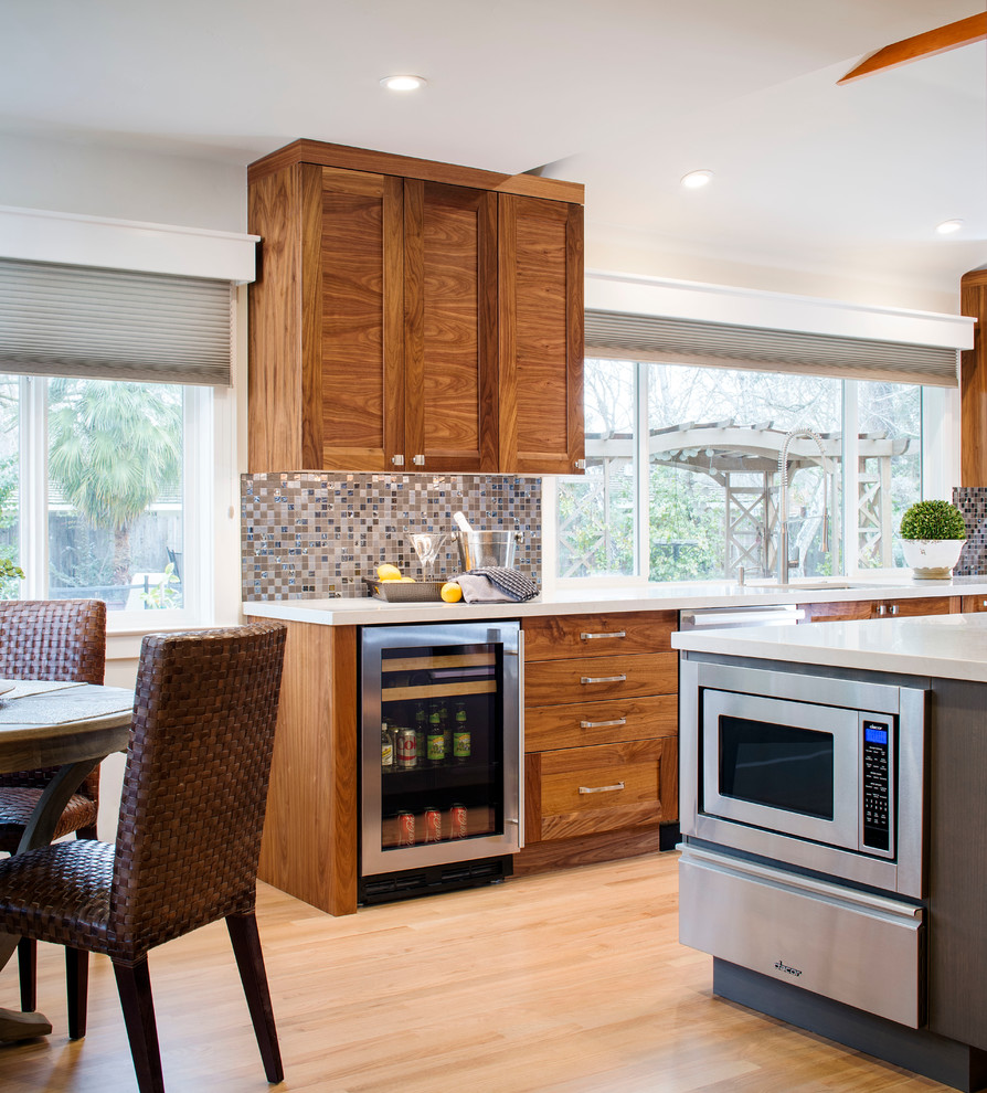 Inspiration for a transitional galley eat-in kitchen in Sacramento with an undermount sink, shaker cabinets, medium wood cabinets, quartz benchtops, black splashback, glass tile splashback, stainless steel appliances, light hardwood floors and with island.