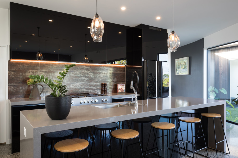 Mid-sized contemporary galley eat-in kitchen in Other with an undermount sink, flat-panel cabinets, black cabinets, quartz benchtops, metallic splashback, ceramic splashback, black appliances, concrete floors, with island, grey benchtop and grey floor.