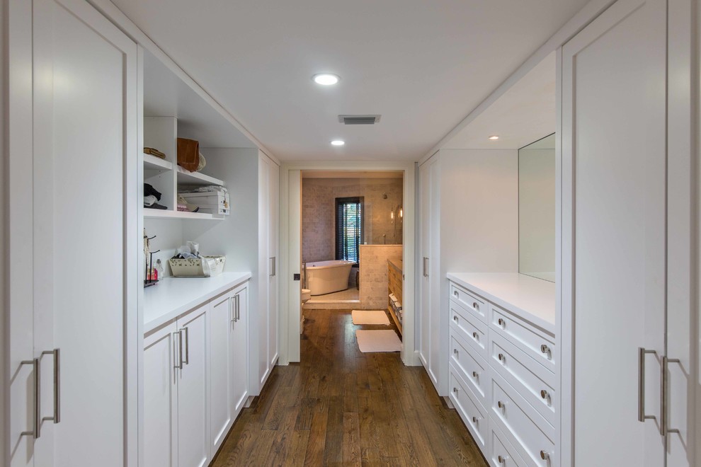 Photo of a mid-sized eclectic gender-neutral dressing room in Miami with recessed-panel cabinets, white cabinets and medium hardwood floors.