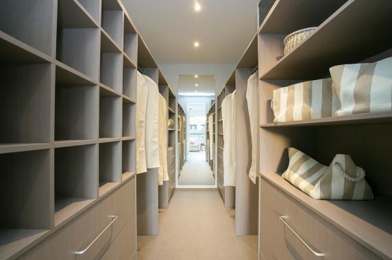 This is an example of a large beach style gender-neutral dressing room in Melbourne with open cabinets, light wood cabinets, carpet and brown floor.