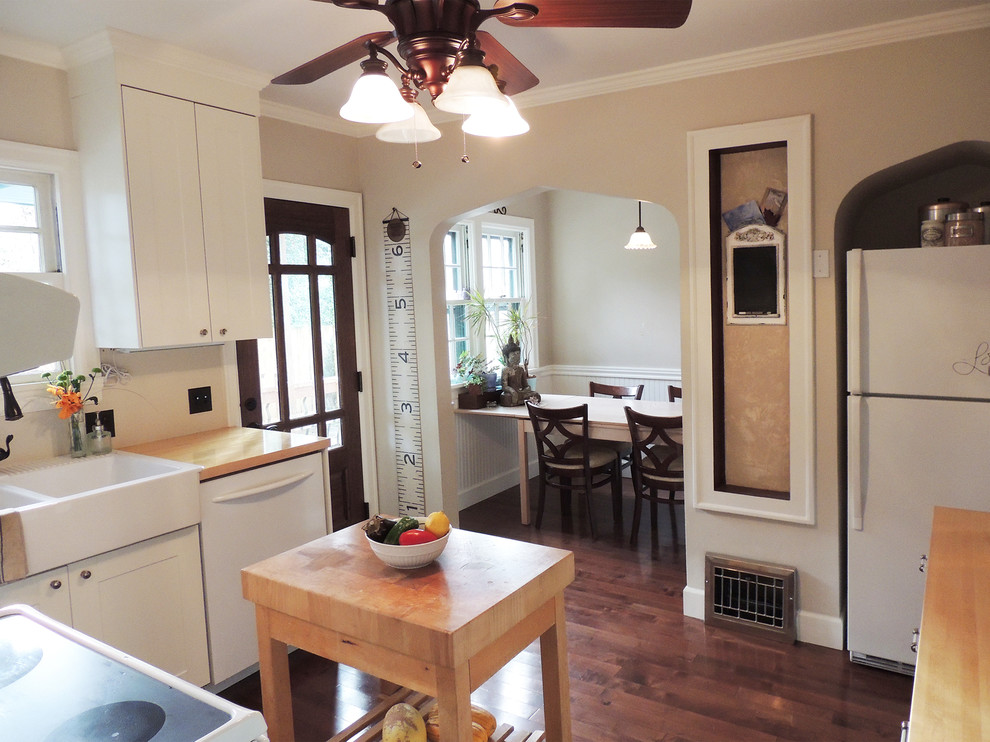 Enclosed kitchen - small transitional u-shaped dark wood floor enclosed kitchen idea in Portland with an integrated sink, shaker cabinets, white cabinets, wood countertops, white appliances and an island