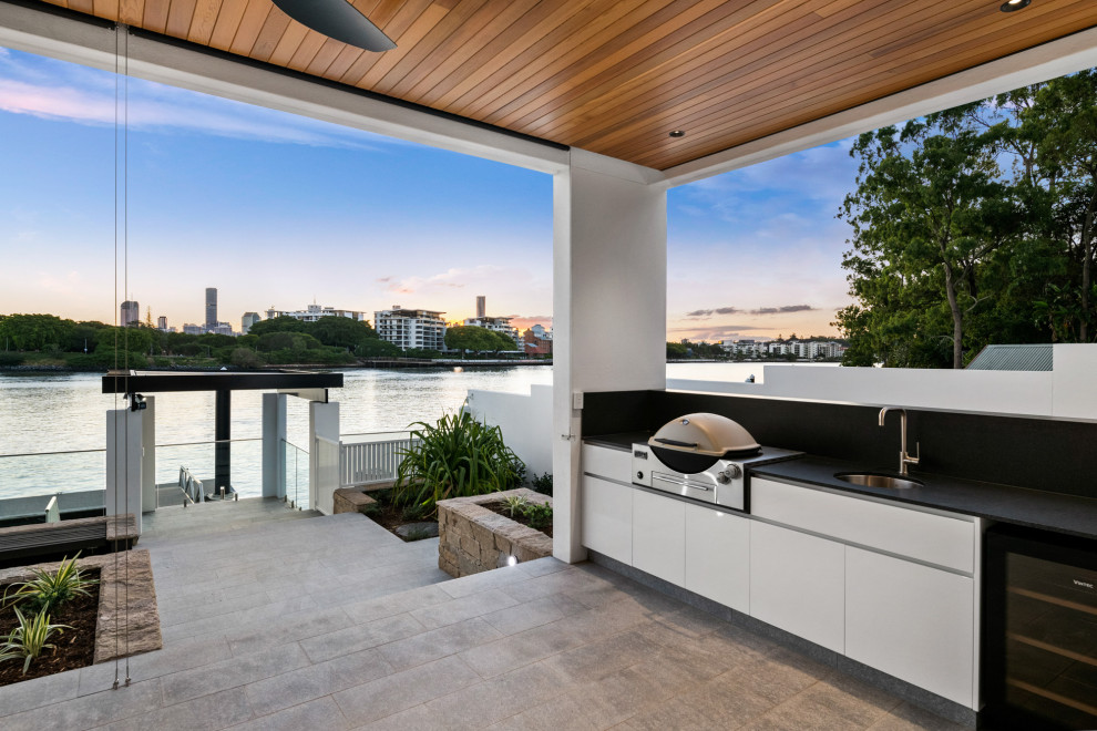 Photo of a large modern backyard deck in Brisbane with an outdoor kitchen and a roof extension.