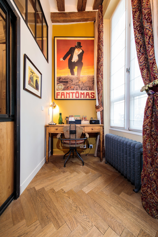 This is an example of an industrial study room in Paris with yellow walls, medium hardwood floors, no fireplace, a freestanding desk and brown floor.
