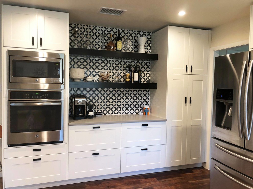 This is an example of a mid-sized country u-shaped eat-in kitchen in Austin with an undermount sink, shaker cabinets, yellow cabinets, quartzite benchtops, white splashback, subway tile splashback, stainless steel appliances, medium hardwood floors, a peninsula and grey benchtop.