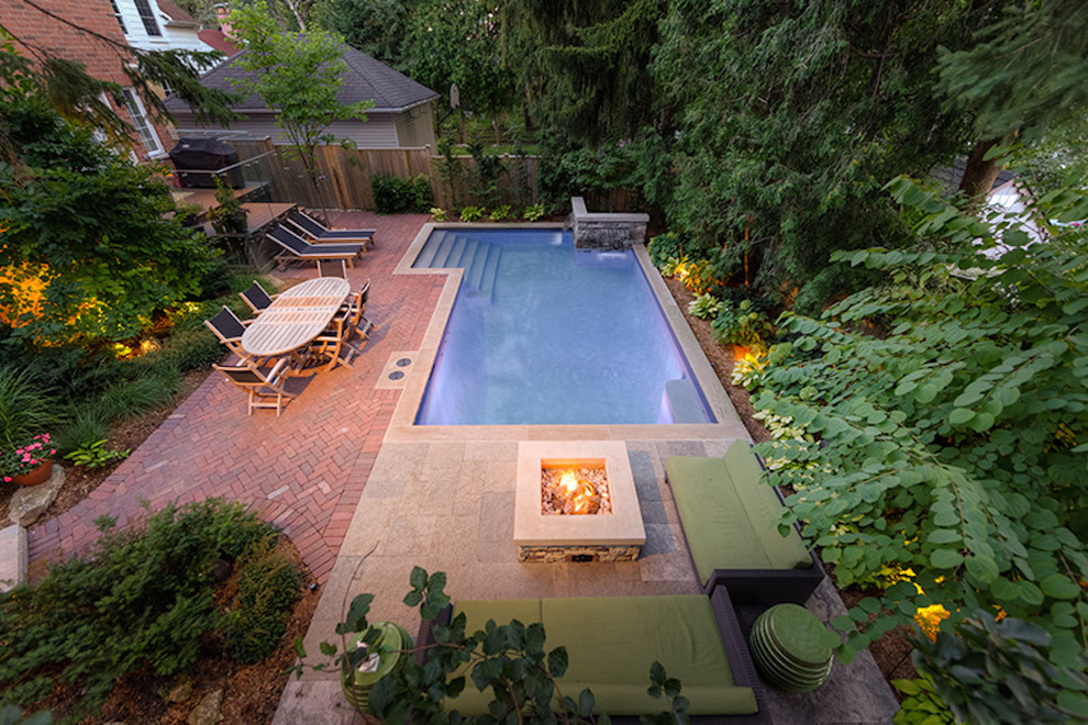 Inspiration for a mid-sized transitional backyard l-shaped natural pool in Toronto with brick pavers and a hot tub.