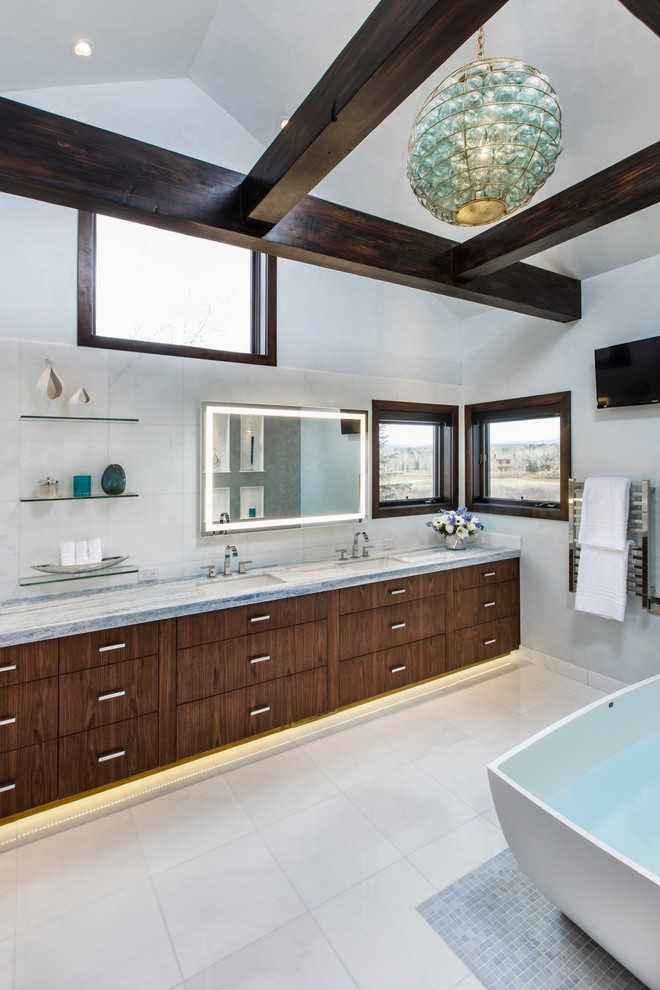 Inspiration for a large contemporary master bathroom in Denver with an undermount sink, flat-panel cabinets, dark wood cabinets, a freestanding tub, white walls, an alcove shower, a two-piece toilet, white tile, subway tile, travertine floors, marble benchtops, beige floor and a hinged shower door.