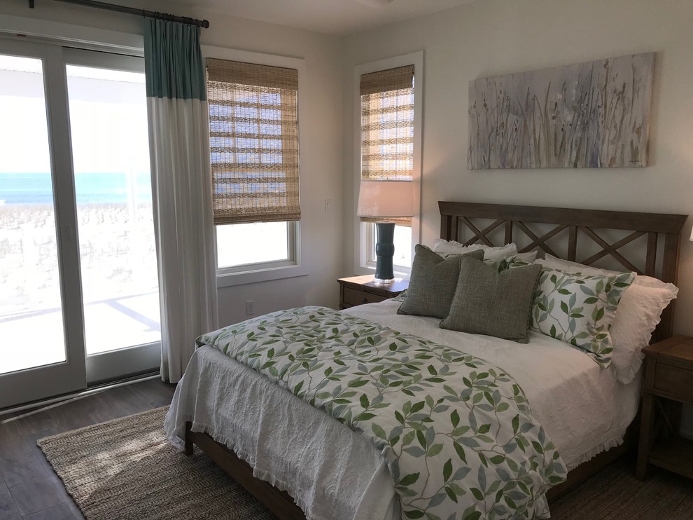 Mid-sized beach style guest bedroom in New York with white walls, medium hardwood floors, no fireplace and brown floor.