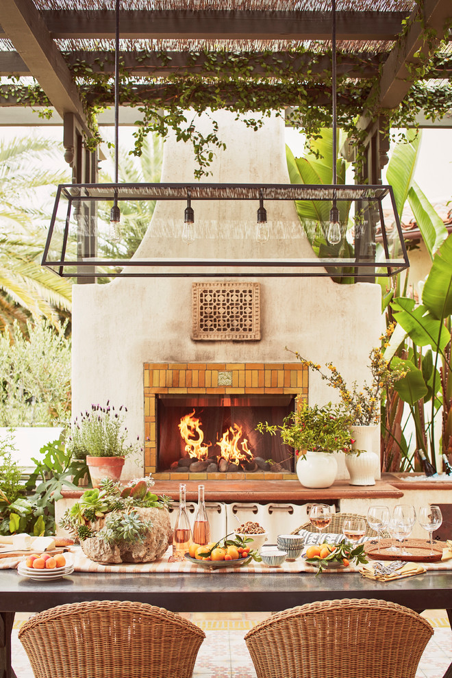 Large mediterranean courtyard patio in Los Angeles with with fireplace, tile and a pergola.