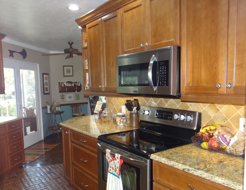 Mid-sized country galley eat-in kitchen in Tampa with an undermount sink, recessed-panel cabinets, dark wood cabinets, granite benchtops, beige splashback, stone tile splashback, stainless steel appliances, ceramic floors and with island.
