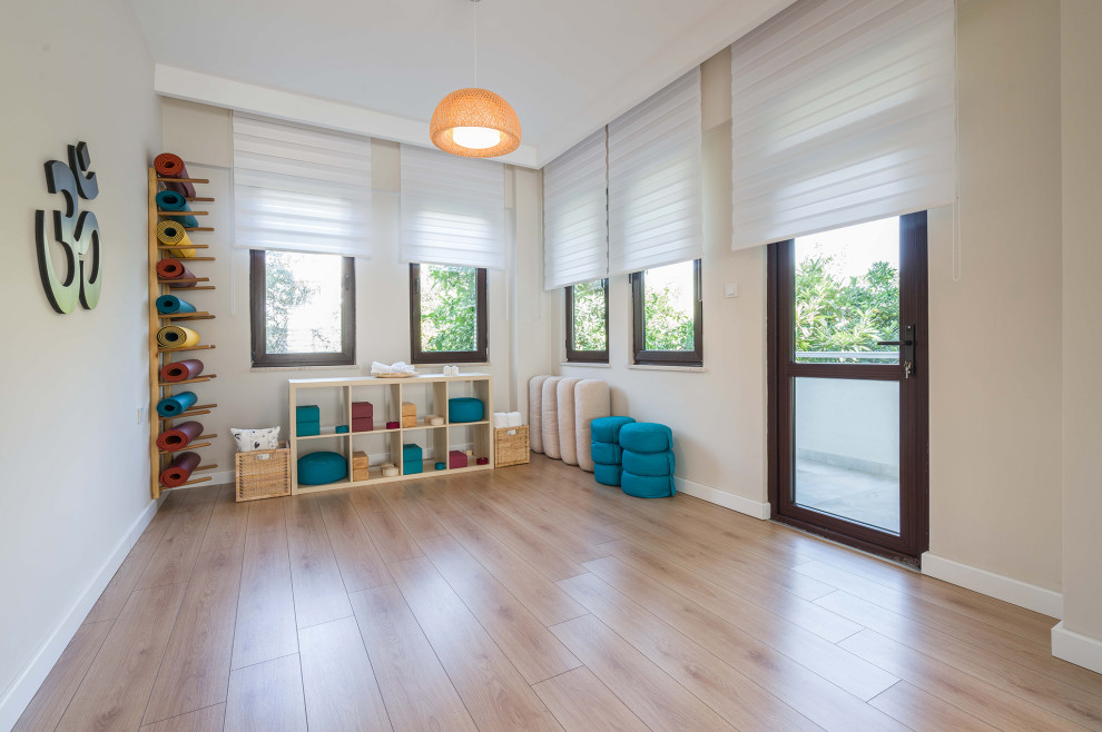 Esempio di uno studio yoga minimalista di medie dimensioni con pareti beige, pavimento in laminato e pavimento beige