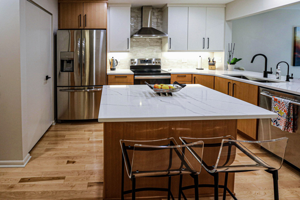 Modern inredning av ett mellanstort vit vitt kök, med en undermonterad diskho, släta luckor, skåp i ljust trä, bänkskiva i kvarts, vitt stänkskydd, stänkskydd i keramik, rostfria vitvaror, ljust trägolv, en köksö och brunt golv