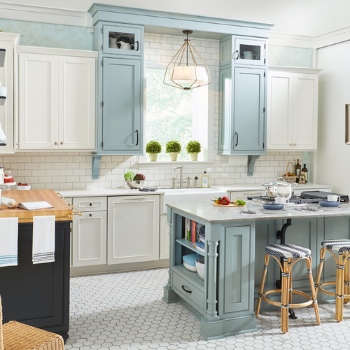 Coastal-style kitchen with white cabinets and soft blue upper cabinetry, white subway tile backsplash, a light blue island with open shelving, and woven counter stools—Kitchen Cabinet Mississauga.